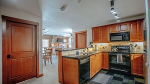 A kitchen with wooden cabinets, a microwave, stove, and a dishwasher. - Apex View by Cottonwood Lodging (Solitude)