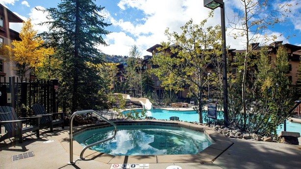 A pool area with lounge chairs, a hot tub, and a waterfall feature. - Apex View by Cottonwood Lodging (Solitude)