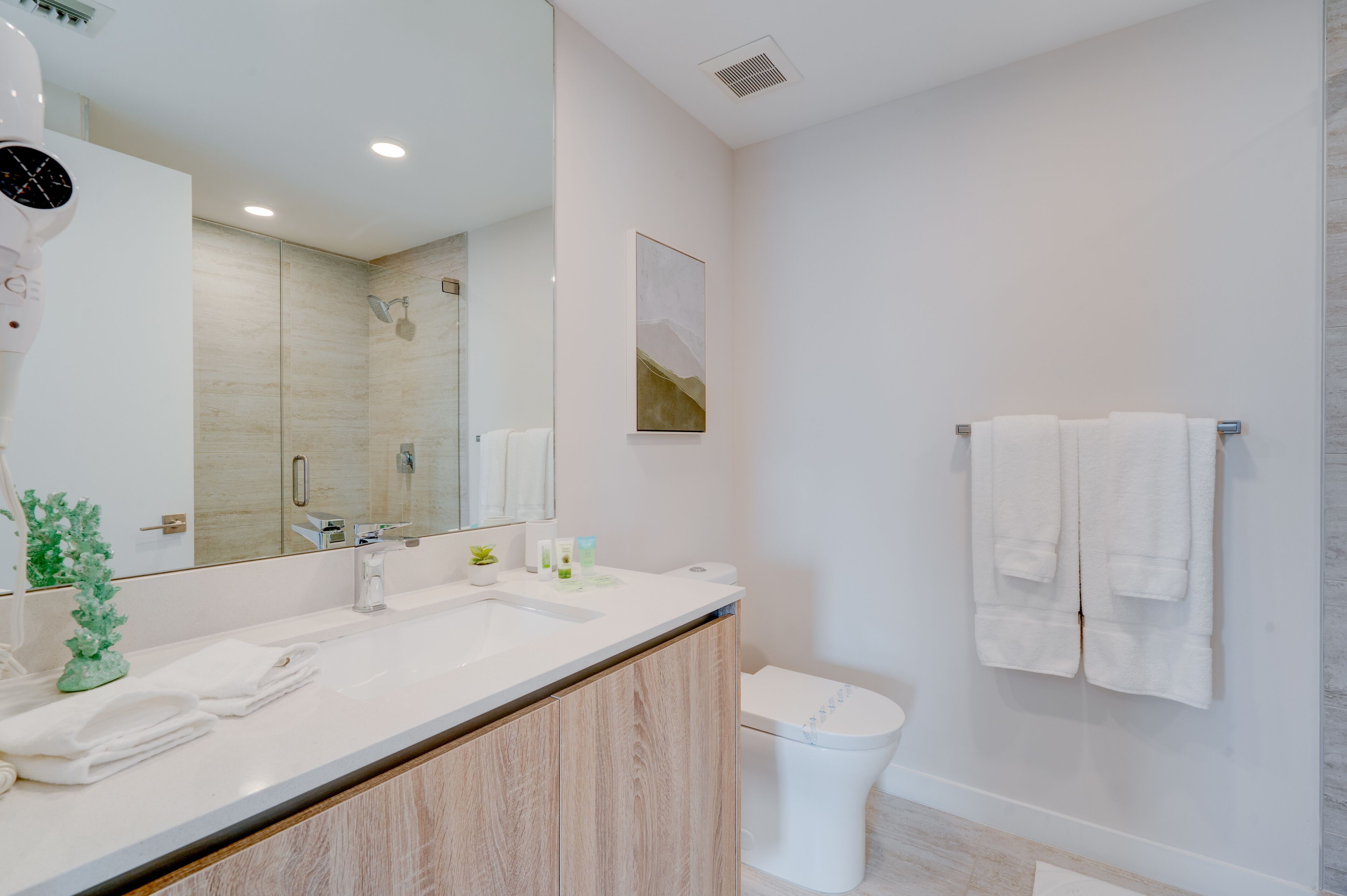 A modern bathroom with a large mirror, a sink, a toilet, and a towel rack.