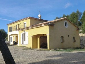 A two-story yellow building with a tiled roof, a satellite dish, and a garage.