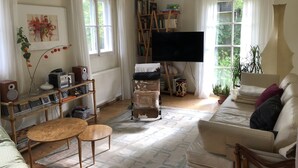 Ein gemütliches Wohnzimmer mit einer Couch, einem Couchtisch, einem Bücherregal, einem Flachbildfernseher und einer Heizung.