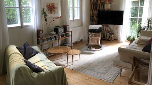 Ein gemütliches Wohnzimmer mit einer Couch, einem Couchtisch, einem Fernseher und einem Bücherregal voller Bücher und Dekorationen.