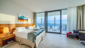 A hotel room with a bed, a nightstand, a desk, a chair, and a view of the sea. - Villa Valiosa - stunning beachfront villa with a pool and a sauna for ten guests by MyWaycation (Rogoznica)