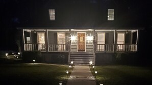 A house with a front porch, a staircase leading to the entrance, and a pathway with lights.