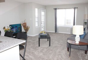 Relax in this stylish living room with a flat-screen TV, comfortable sofa, and dining area.