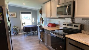 A modern kitchen with stainless steel appliances, a granite countertop, and a dining area with a table and chairs.