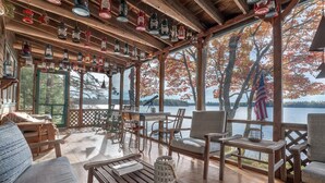 Une terrasse en bois avec des sièges d’extérieur, une vue sur un lac et des lanternes suspendues.