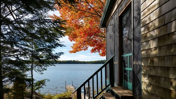 Une cabane en bois avec un escalier menant à une terrasse d’où l’on a vue sur un lac.