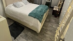 A bedroom with a bed, a ceiling fan, a bedside table, a mirror, and a staircase. - Tampa River Oasis (Tampa)