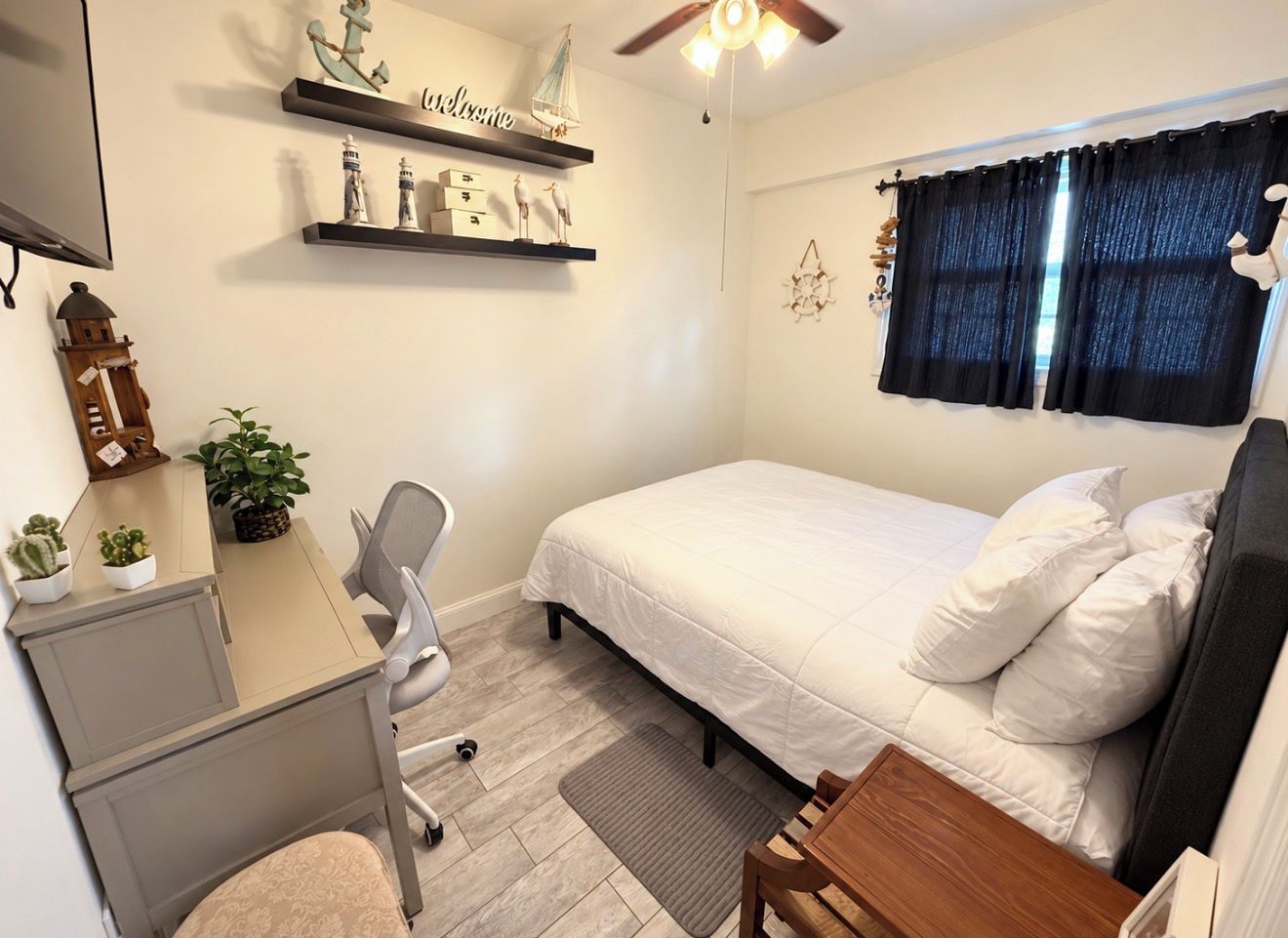 A bedroom with a bed, desk, chair, and shelving with decorative items.