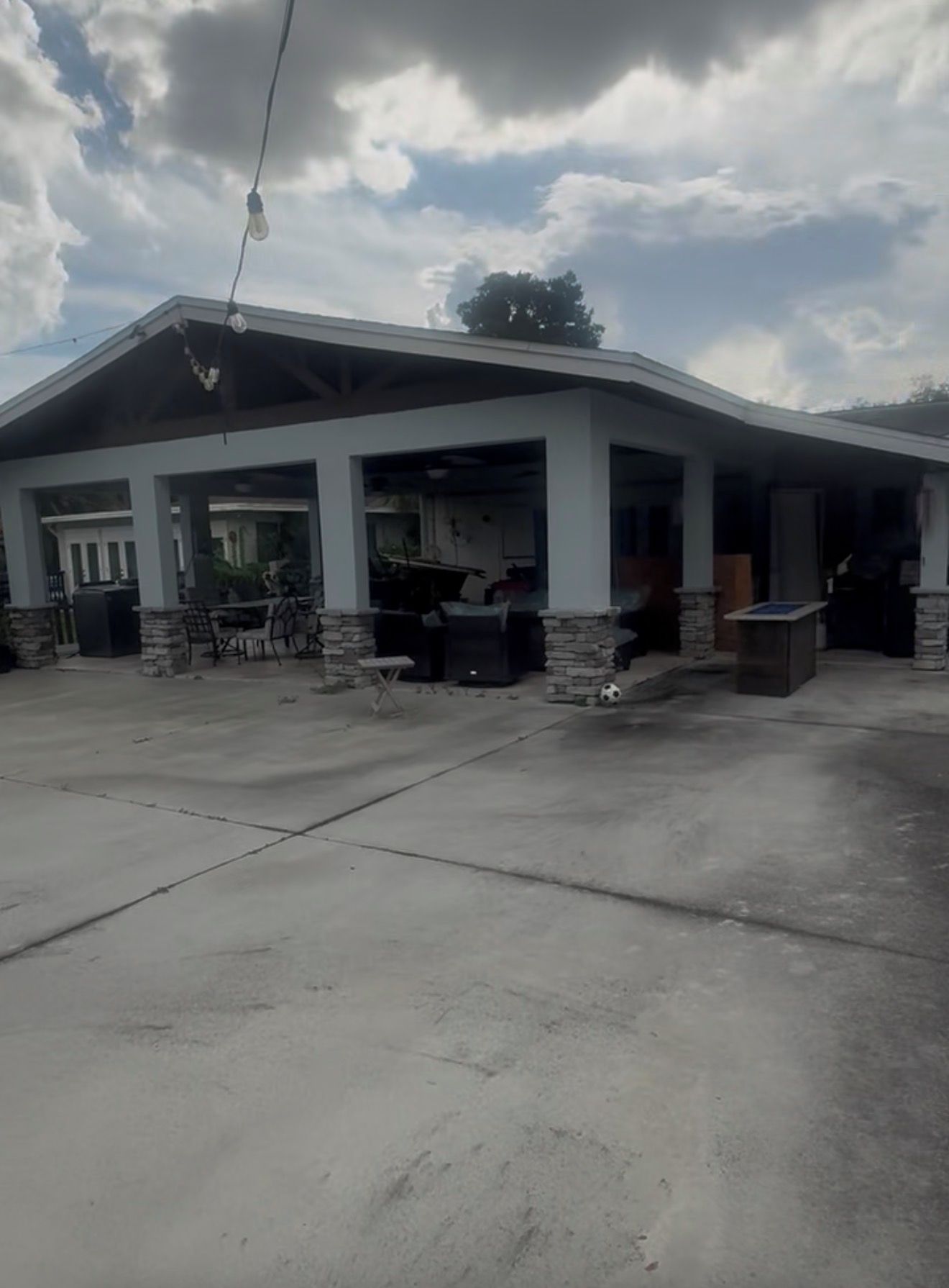 A covered outdoor area with a patio, seating, and a stone column.