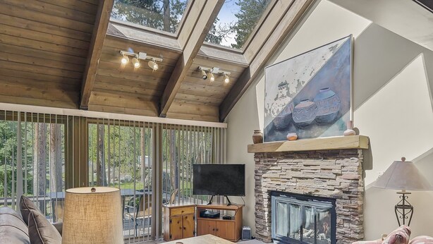 Ein gemütliches Wohnzimmer mit Kamin aus Stein, einem Fernseher und bequemen Sitzmöglichkeiten.