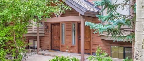 A wooden cabin with a front porch, a door, and a window.
