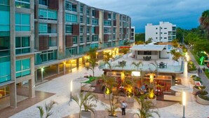 A modern hotel with a central courtyard, outdoor seating, and a pool area. - Stylish Duplex Retreat 2BR Pool Nuevo Vallarta (Nuevo Vallarta)
