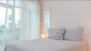 A bedroom with a large bed, two pillows, a bedside table, and a window with sheer curtains. - Stylish Duplex Retreat 2BR Pool Nuevo Vallarta (Nuevo Vallarta)