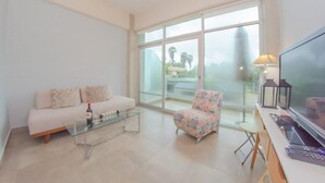 A modern living room with a sofa, a patterned armchair, a glass coffee table, and a TV on a stand. - Stylish Duplex Retreat 2BR Pool Nuevo Vallarta (Nuevo Vallarta)
