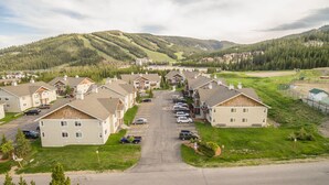 Zona residencial con casas, un estacionamiento y una carretera que se dirige hacia un fondo montañoso.