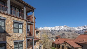 A multi-story building with stone facade and balconies, set against a backdrop of snow-capped mountains. - CASSIDY'S HIDEOUT- Beautiful Condo with Amazing San Sophia Ridge Views (Mountain Village)