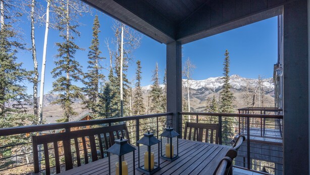 A wooden deck with a table and chairs, three lanterns, and a mountain view. - CASSIDY'S HIDEOUT- Beautiful Condo with Amazing San Sophia Ridge Views (Mountain Village)