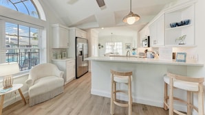 A modern kitchen with a large island, white cabinetry, and a ceiling fan. - Osprey in Blue Lagoon Unit 6 - Condo with Pool - By Island Real Estate Vacations (Holmes Beach)