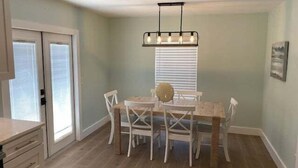 A dining area with a table and chairs, a ceiling light fixture, and a window with blinds. - Beach Life by the Gulf- Charming & Fully Equipped! (Redington Beach)