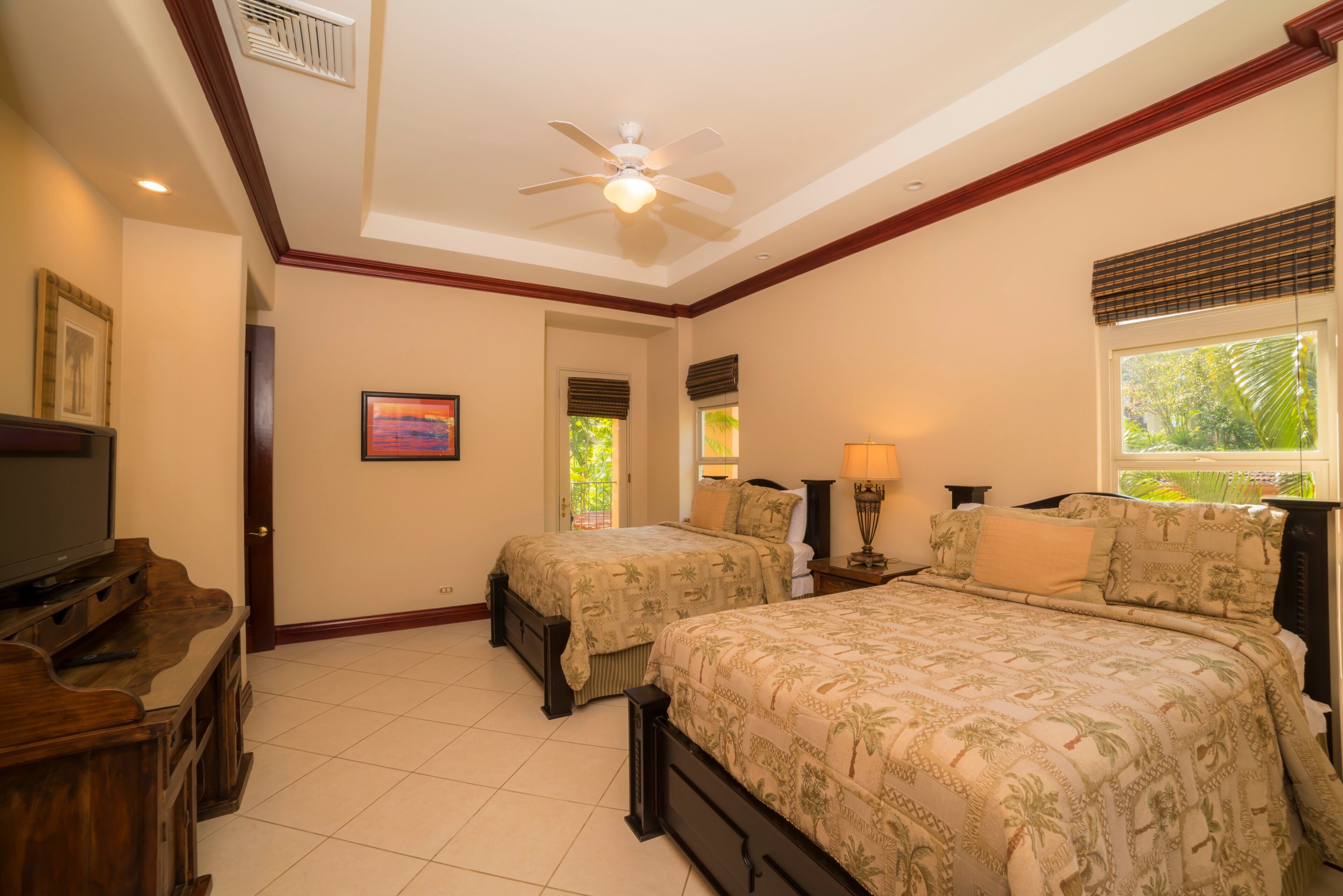 A bedroom with two beds, a ceiling fan, a TV, and a window with blinds.