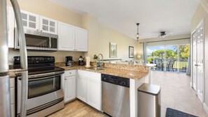A modern kitchen with stainless steel appliances, white cabinetry, and a view to a balcony. - Waterfront Duck Key Villa - Sleeps 6 (Duck Key)