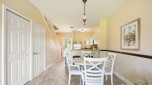 A dining area with a white table and chairs, a chandelier, and a framed painting on the wall. - Waterfront Duck Key Villa - Sleeps 6 (Duck Key)