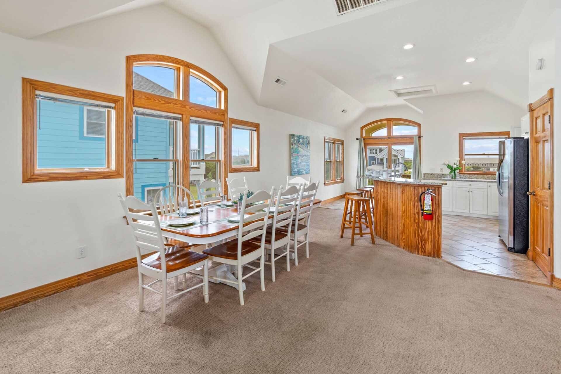 A spacious kitchen with a large island, white cabinetry, and a view of the outside.