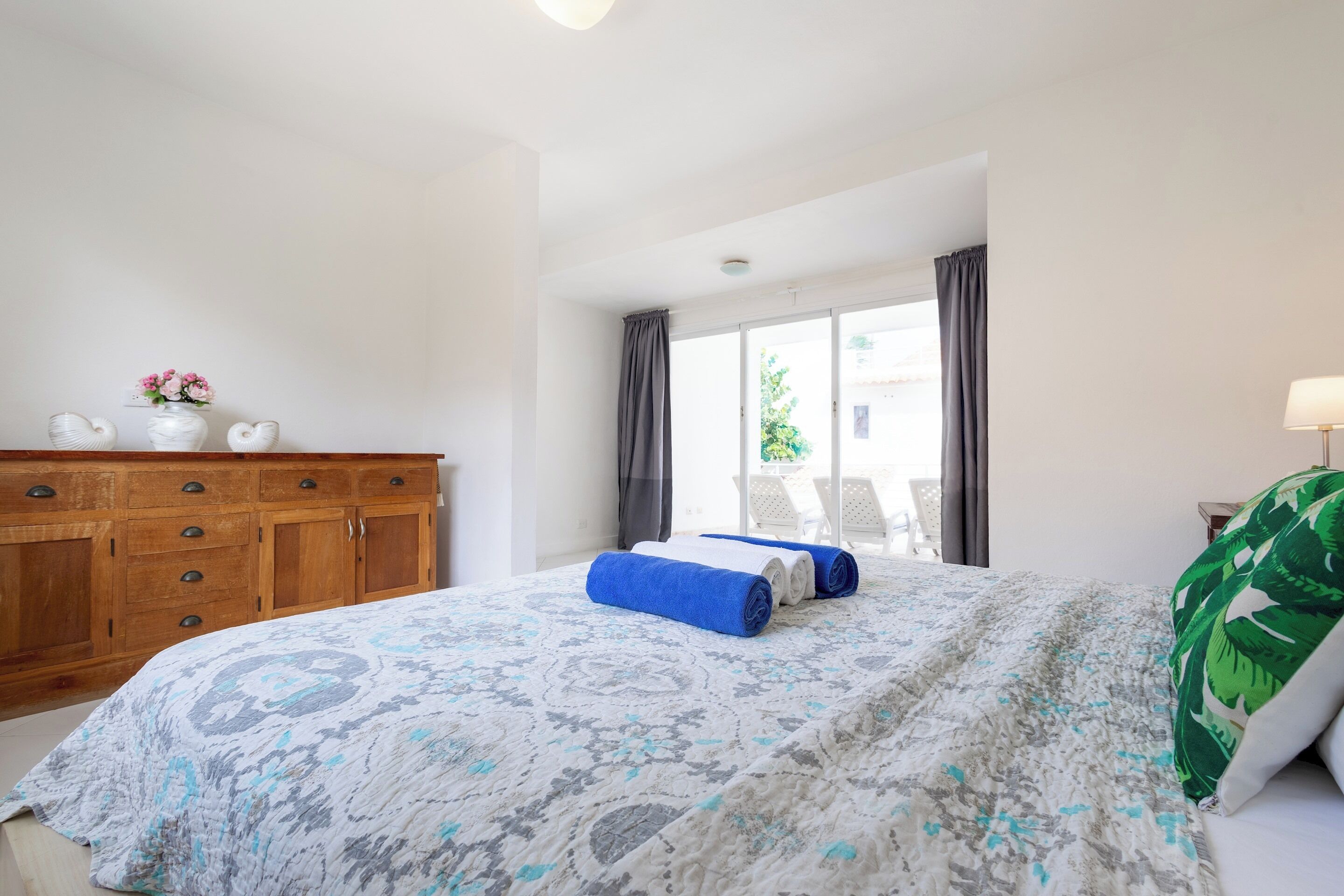 Une chambre avec un grand lit, une armoire en bois et une vue sur l’extérieur.