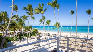 A beach with palm trees, a clear blue sky, and a view of the ocean. - Ocean View Luxury Apartment Directly on the Los Corales Beach (Punta Cana)