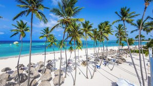 A beach with palm trees and a clear blue sky. - Punta Cana Beachfront Penthouse - Ocean View, BBQ, Terrace, 4BR (Punta Cana)