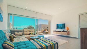 Un salon moderne avec un grand canapé, une table basse et un téléviseur.