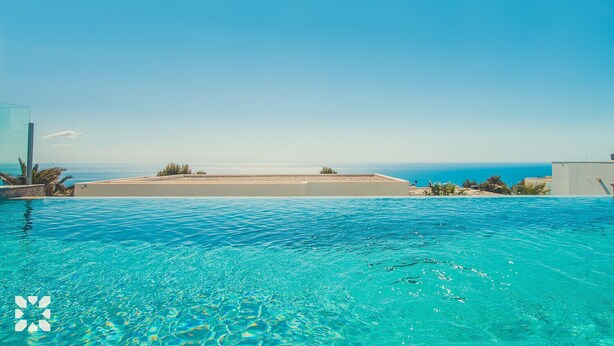 Une piscine d’un bleu éclatant, avec vue sur la mer et une plage qui s’étend au loin.
