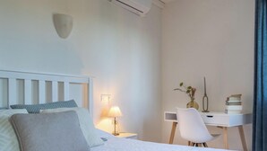A bedroom with a bed, bedside table, lamp, desk, chair, and a wall-mounted light fixture. - Villa GOOD VIBES by Abahana Villas (Benissa)