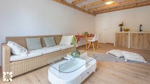 A living room with a wicker sofa, a glass coffee table, and a dining area with a wooden table and chairs. - Villa GOOD VIBES by Abahana Villas (Benissa)