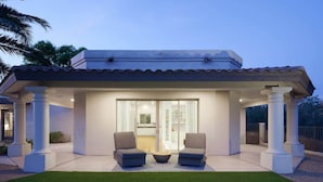 Una casa moderna con un porche cubierto, dos sofás y una puerta de vidrio que da al interior.