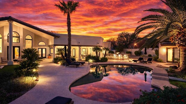 Un resort moderno con piscina, zona de estar al aire libre y vistas al atardecer.