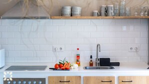 A modern kitchen with white tiles, a stainless steel sink, and wooden cabinets. - Villa CASA PIPA by Abahana Villas (Benissa)