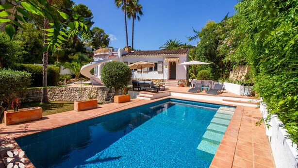 A swimming pool with a sun terrace, surrounded by lush greenery and palm trees. - Villa CASA PIPA by Abahana Villas (Benissa)