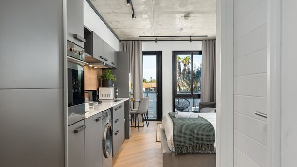 Une cuisine moderne équipée d’un four encastré, d’un lave-linge et d’un coin repas avec une chaise et une table.