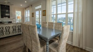 A dining area with a table and chairs, large windows, and a view of the outdoors. - 87 Ocean Creek - Canal w/Shared Dock (Fripp Island)