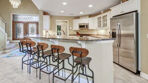 A modern kitchen with a central island, stainless steel appliances, and bar stools. - 3rd Row Ocean - Dog Friendly Sea Pines Home w/ FREE Pool Heat Seasonally! (Hilton Head Island)