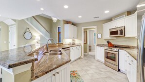 A kitchen with granite countertops, white cabinets, a built-in oven, and a microwave. - 3rd Row Ocean - Dog Friendly Sea Pines Home w/ FREE Pool Heat Seasonally! (Hilton Head Island)