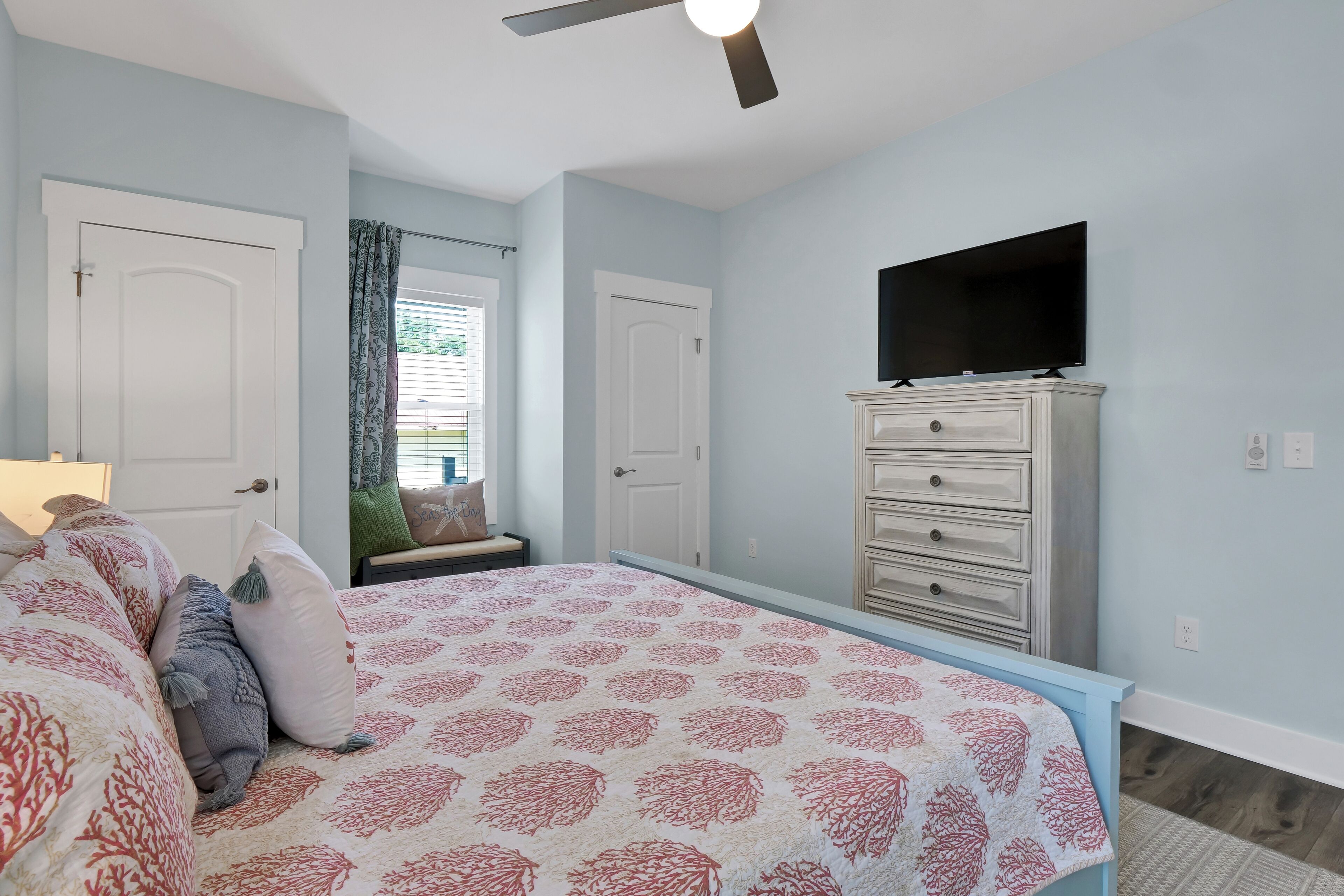 Un dormitorio con cama, cómoda, televisión y ventilador de techo.
