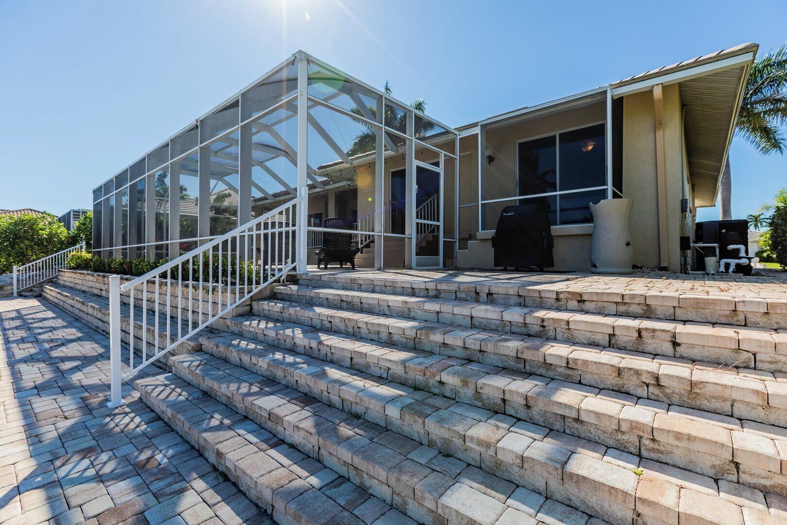 Un bâtiment moderne doté d’une façade vitrée, d’un espace extérieur aménagé pour s’asseoir et d’un coin barbecue.