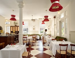 Un comedor con mesas dispuestas para el servicio, un camarero atendiendo a los clientes y un suelo con diseño de cuadros.