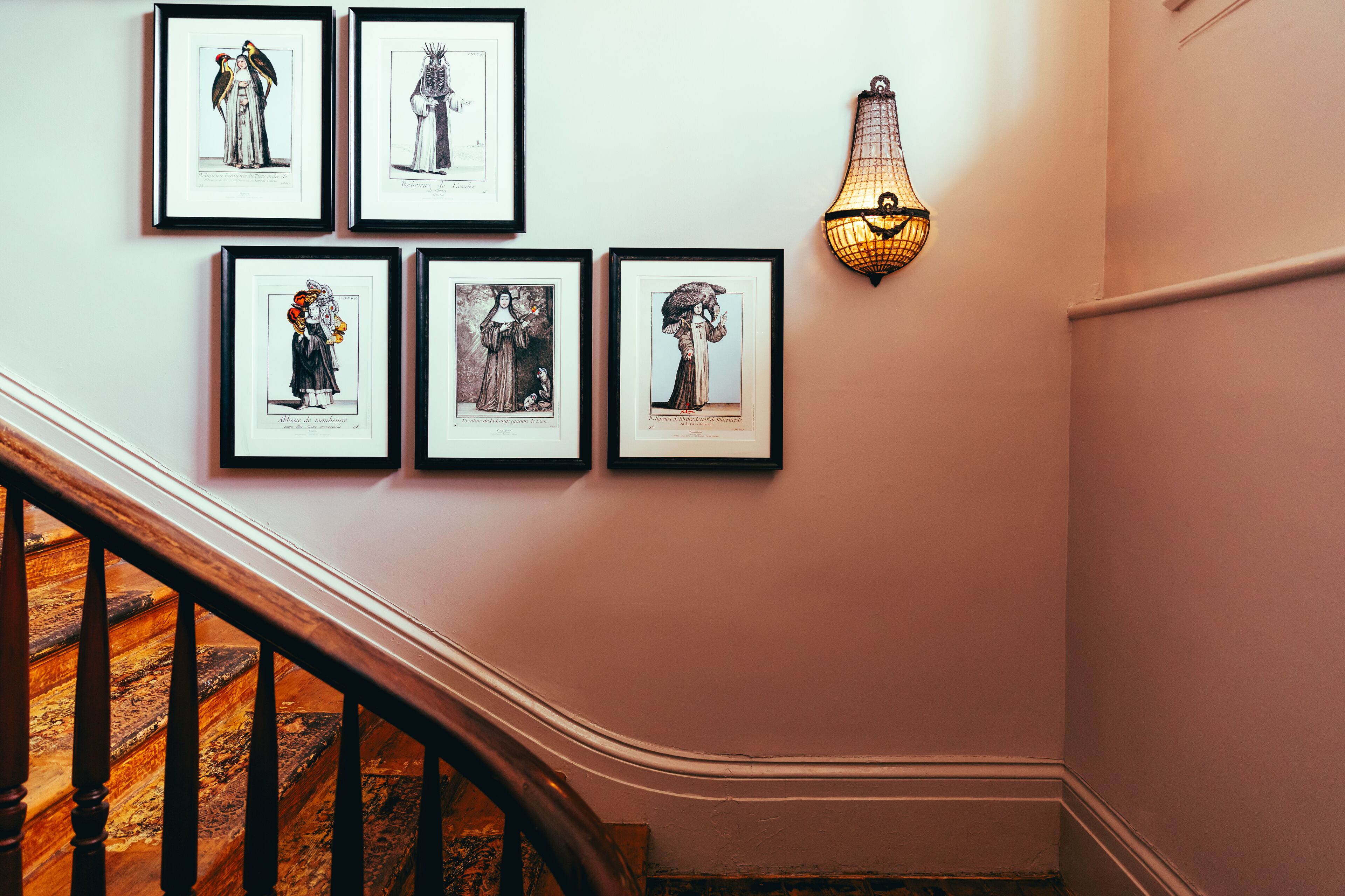 A staircase with wooden railings and a wall adorned with framed botanical illustrations.