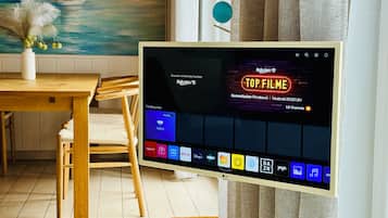 A flat-screen TV displaying a streaming service interface with a prominent 'TOP FILME' section.