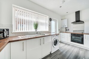 Una cocina moderna con lavadora integrada, estufa y microondas.